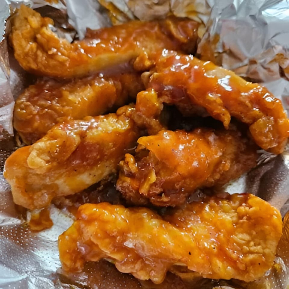 Close-up of several golden-brown Chick Fry halal chicken tenders coated in a glossy orange sauce.