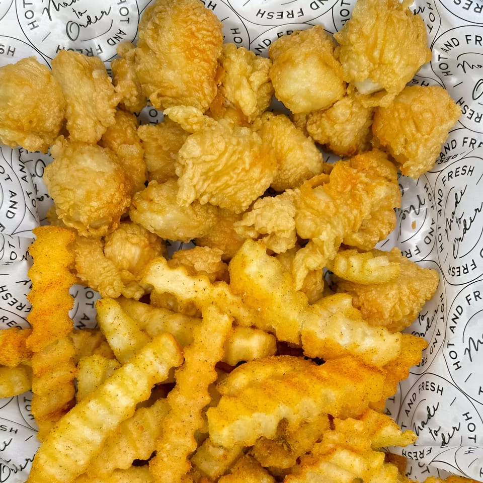 Crispy golden Chick Fry popcorn chicken and seasoned crinkle-cut fries in a paper-lined basket.