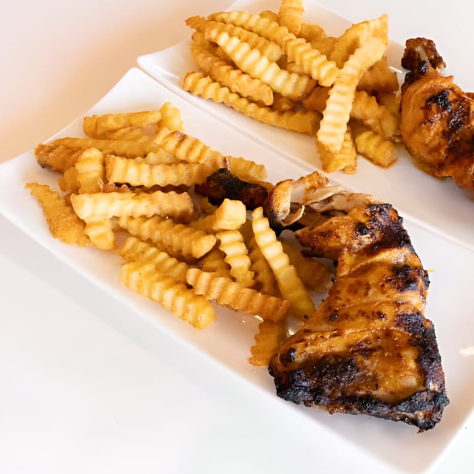 Two white plates with grilled chicken and crinkle-cut fries, showcasing a halal meal from Chick Fry.