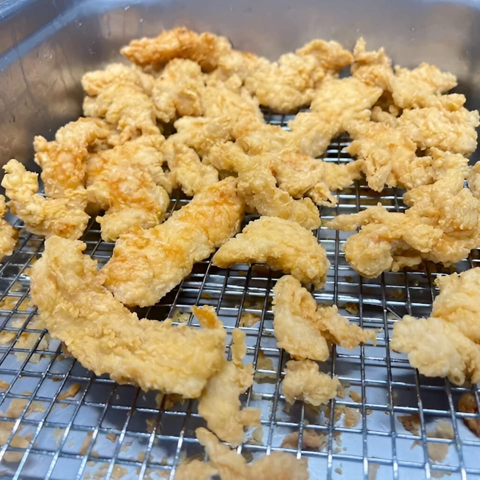 Golden-brown fried chicken pieces, likely halal, resting on a metal cooling rack at Chick Fry.